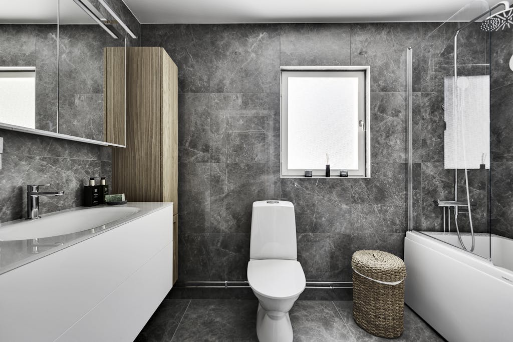 Contemporary bathroom interior featuring grey tiles, a bathtub, and minimalist fixtures.
