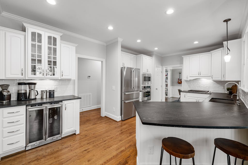Sleek and modern kitchen featuring white cabinets, stainless steel appliances, and hardwood floors.